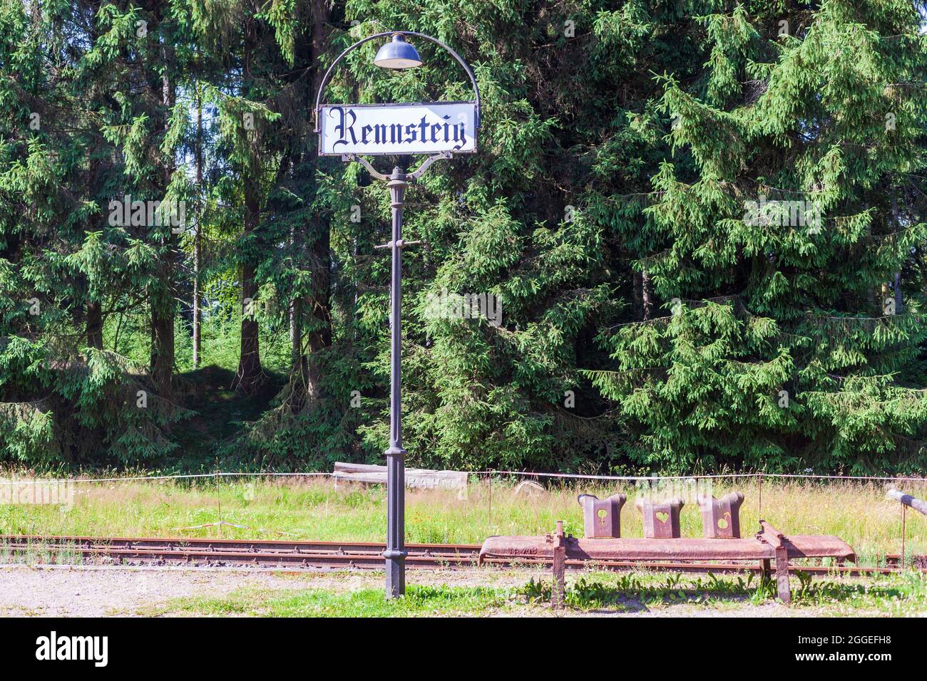 Old station lantern with place name sign and bench made of rusty guardrails. Stock Photo