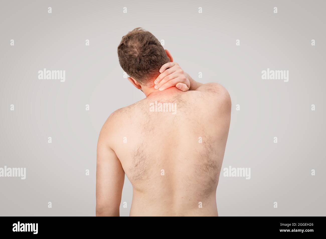 Young man is holding his neck and suffering from pain. High quality photo Stock Photo