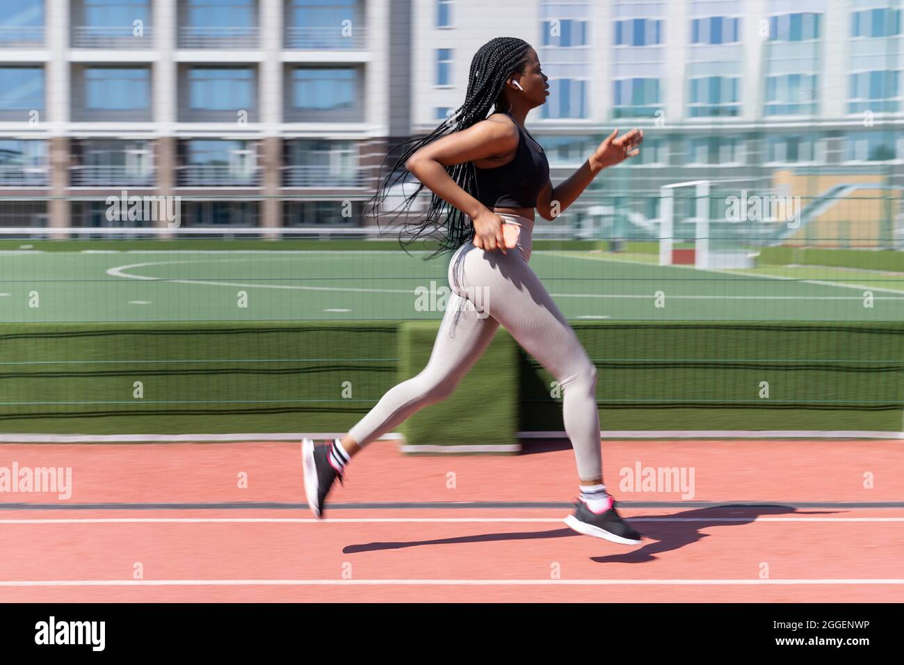 Black girl running outside in stadium at summer, hold cellphone wear