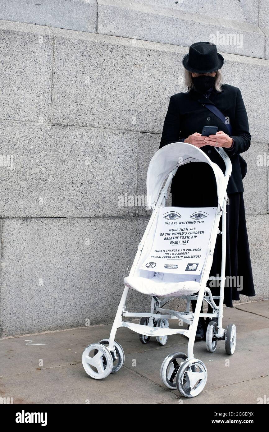 Protestor pictured on their phone as Extinction Rebellion protestors end their Pram Action march at Trafalgar Square. Protestors painted childrenÕs prams white and performed a slow, silent funeral from Parliament Square to Trafalgar Square on the ninth day of their Impossible Rebellion in London, United Kingdom on August 31, 2021. Kieran Riley/Pathos Stock Photo