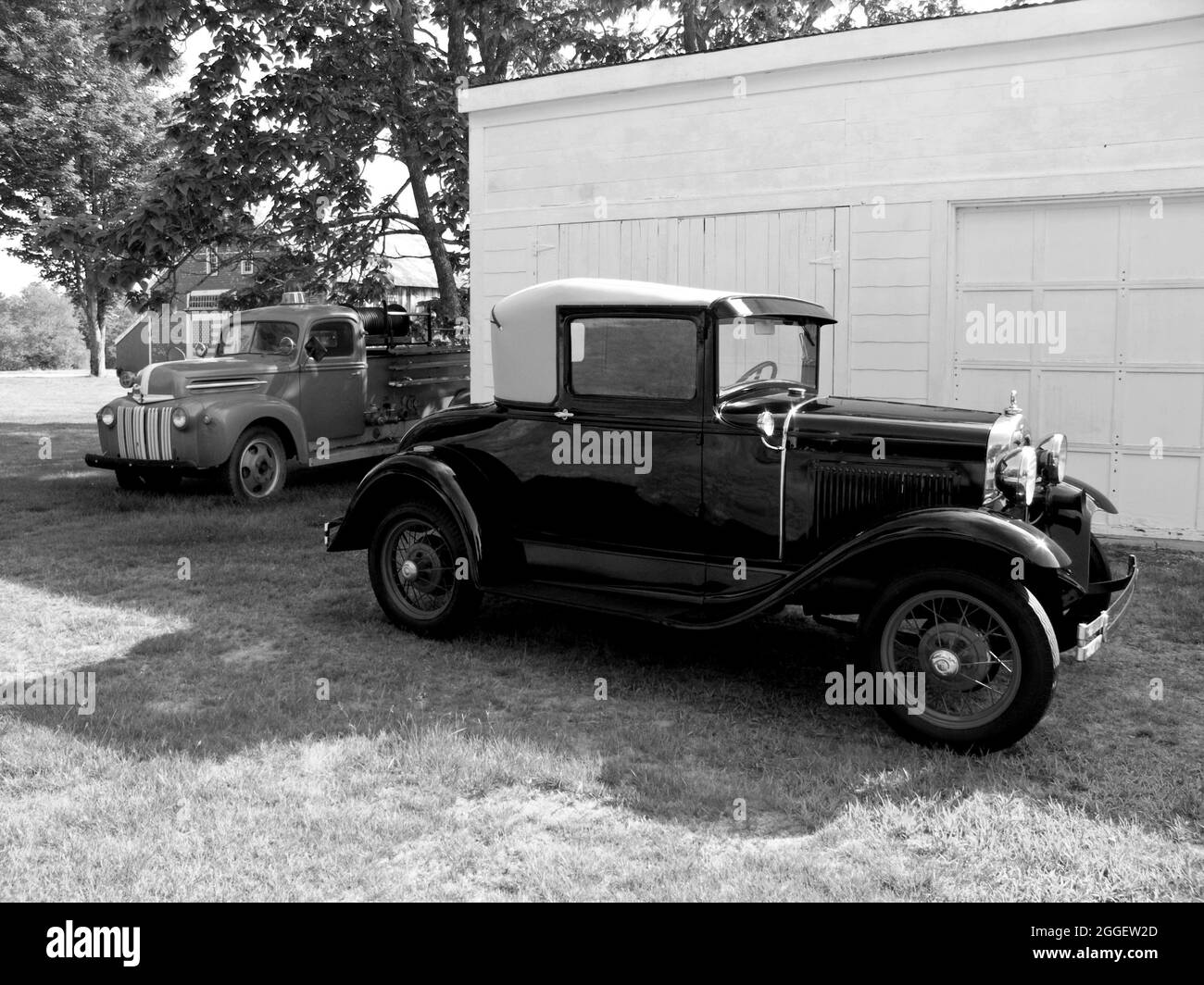 1936 Ford Cabriolet and an 1946 Ford Pick Up Fire Truck by a New England Farm, USA. Stock Photo