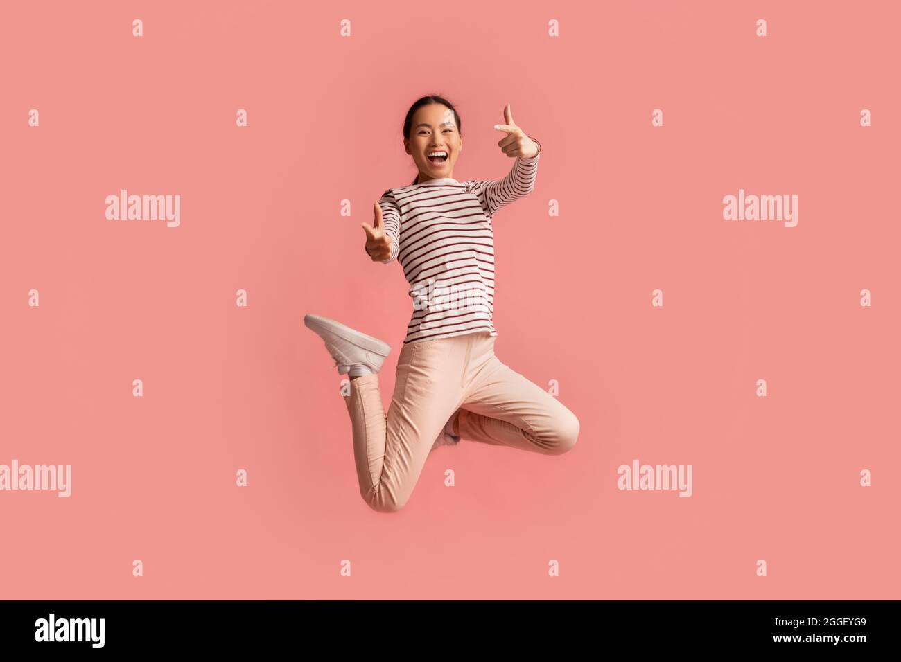Cheerful Asian Female Jumping Up In Air And Pointing At Camera ...