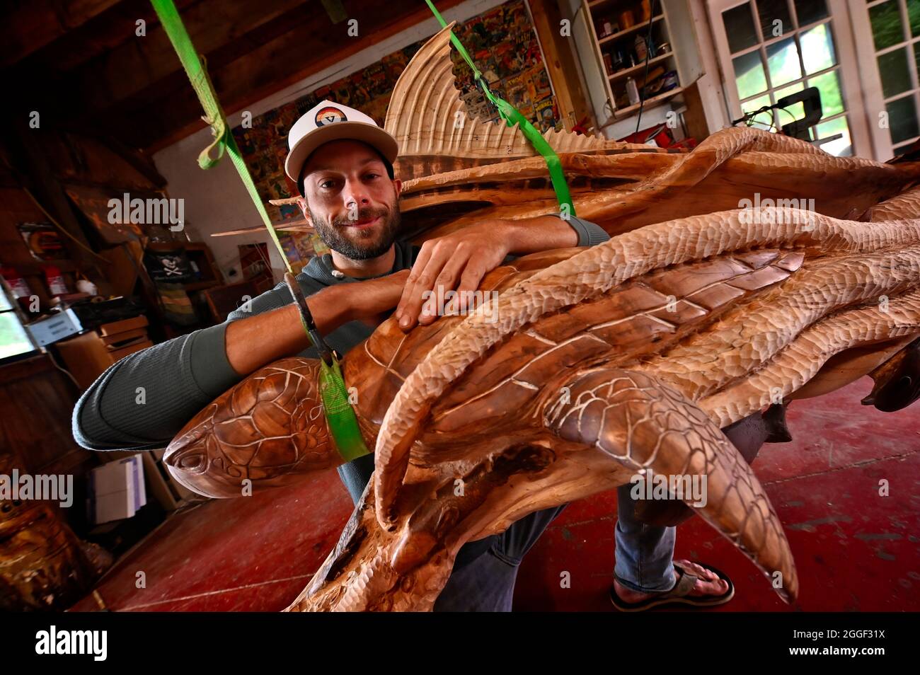UNITED STATES - 07-26-2021: Artist Patrick Burns poses for a photo in his studio with a nautical scene of giant octopus grabbing a dauphin, swordfish Stock Photo