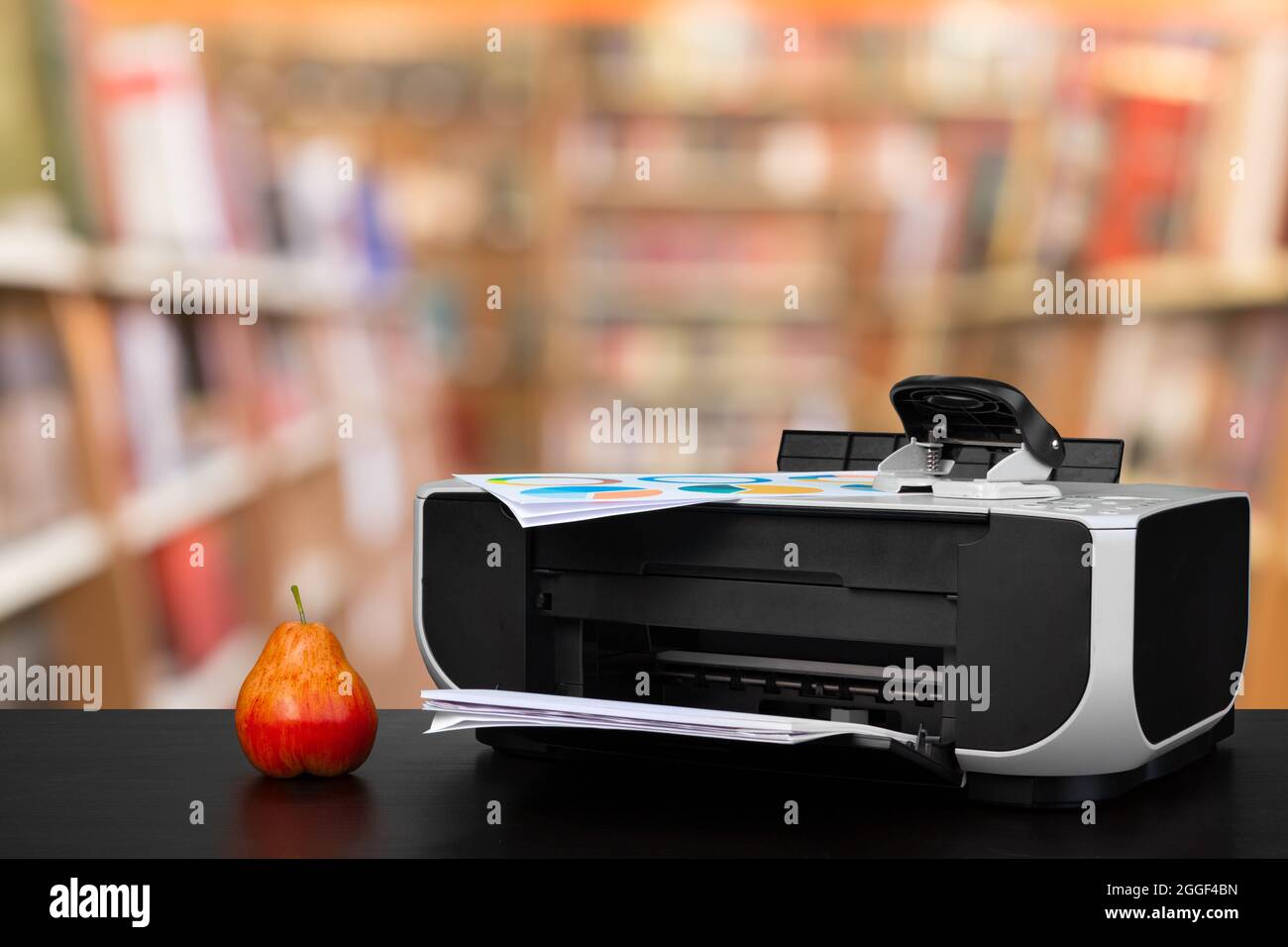 Compact laser printer on black desk against blurred background Stock Photo