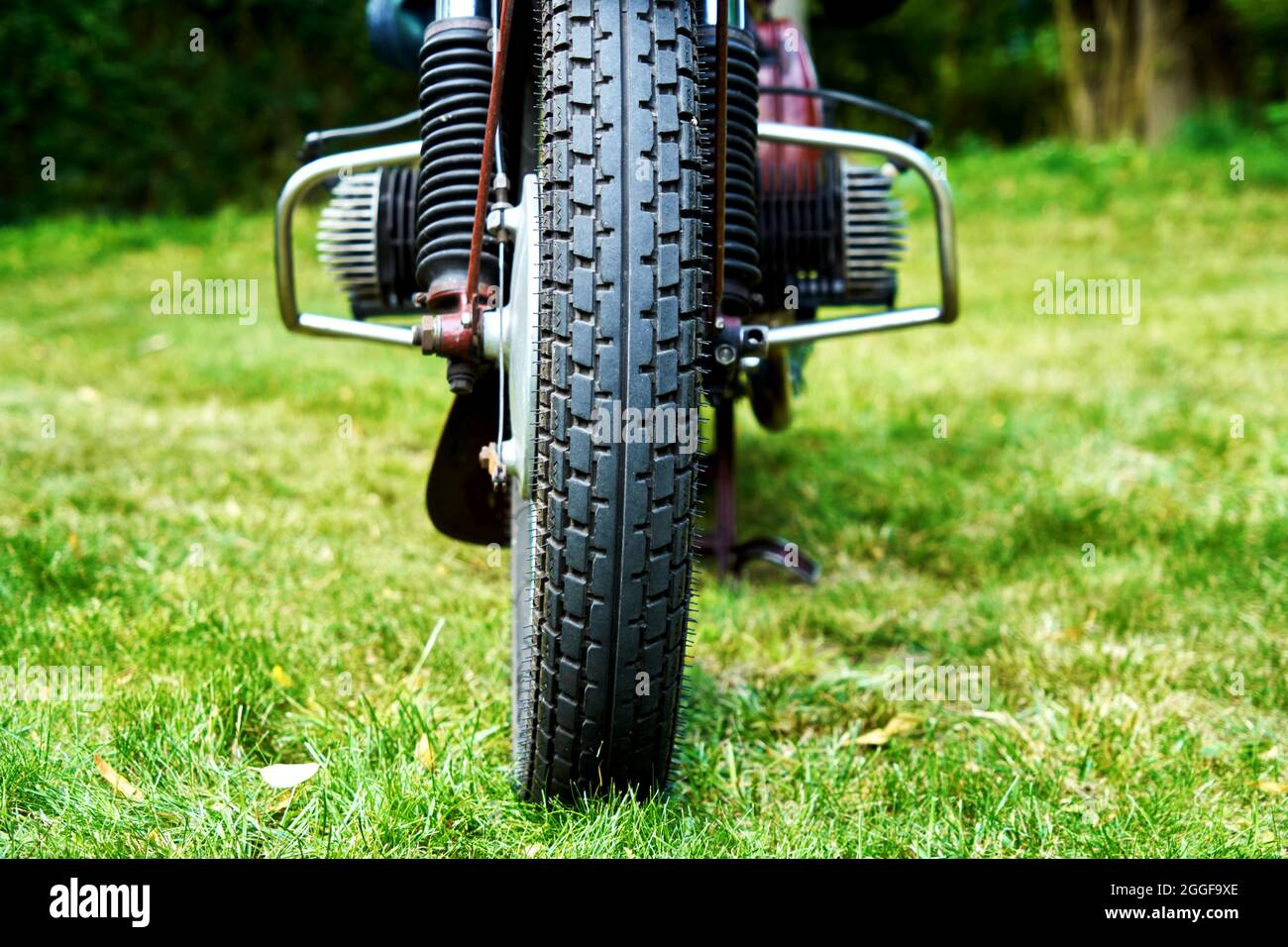 Front tire of antique motorcycle parked on lawn, selective fokus Stock