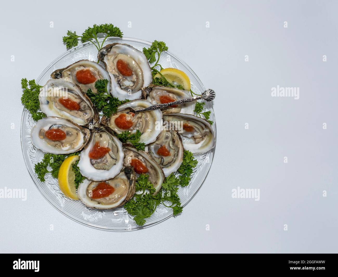 Oysters on the halfshell served on a glass plate with green parsley