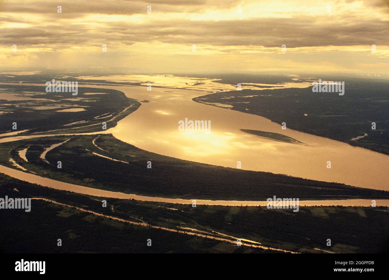 Aerial view of Amazon rain forest - wide river spreads over patches of intact and deforested areas interspersed. Stock Photo