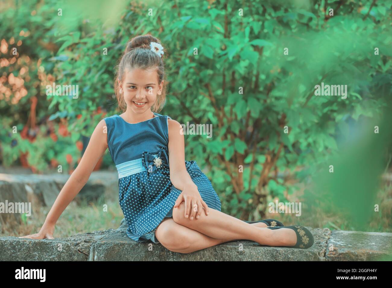 a brunette girl in a blue polka dot dress sitting in the park in the ...