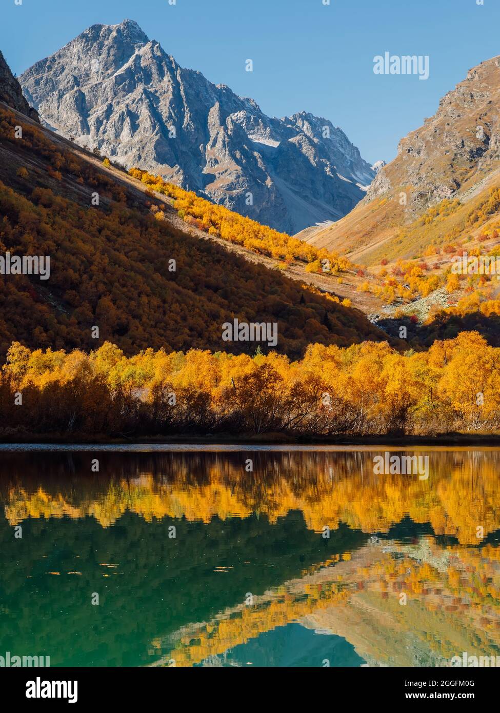 Mountain lake with transparent water and colorful autumnal trees ...