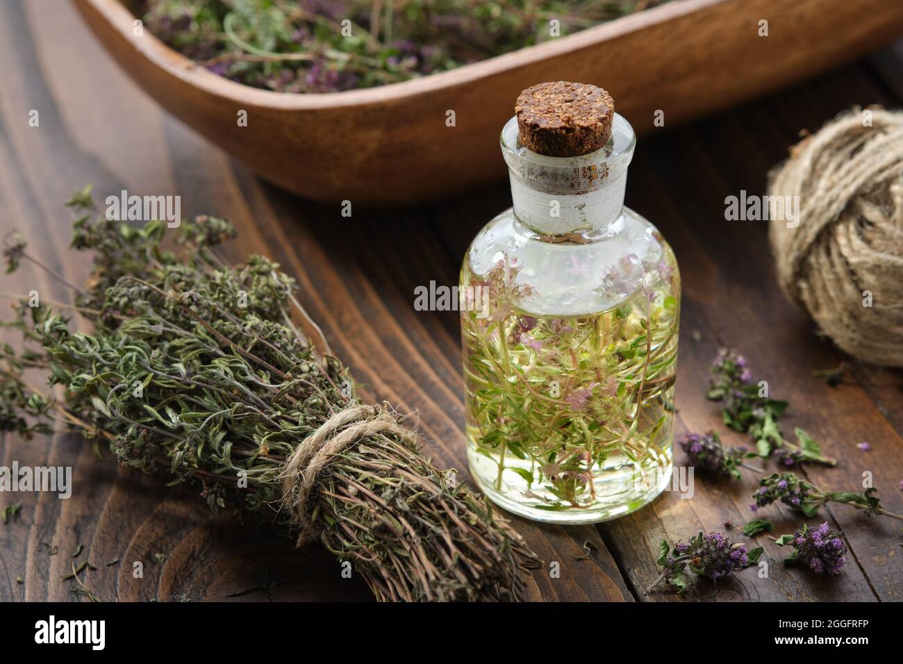 Bottle of thyme essential oil or infusion, bunch of dried thymus serpyllum plants and wooden