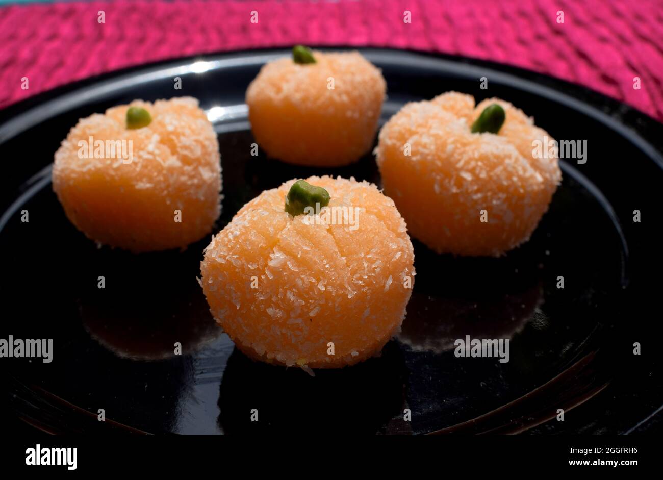 Delicious Orange coconut laddu sweets for festivals like Ganesh chaturthi. Coconut burfi with Orange shape and garnished with pista Stock Photo