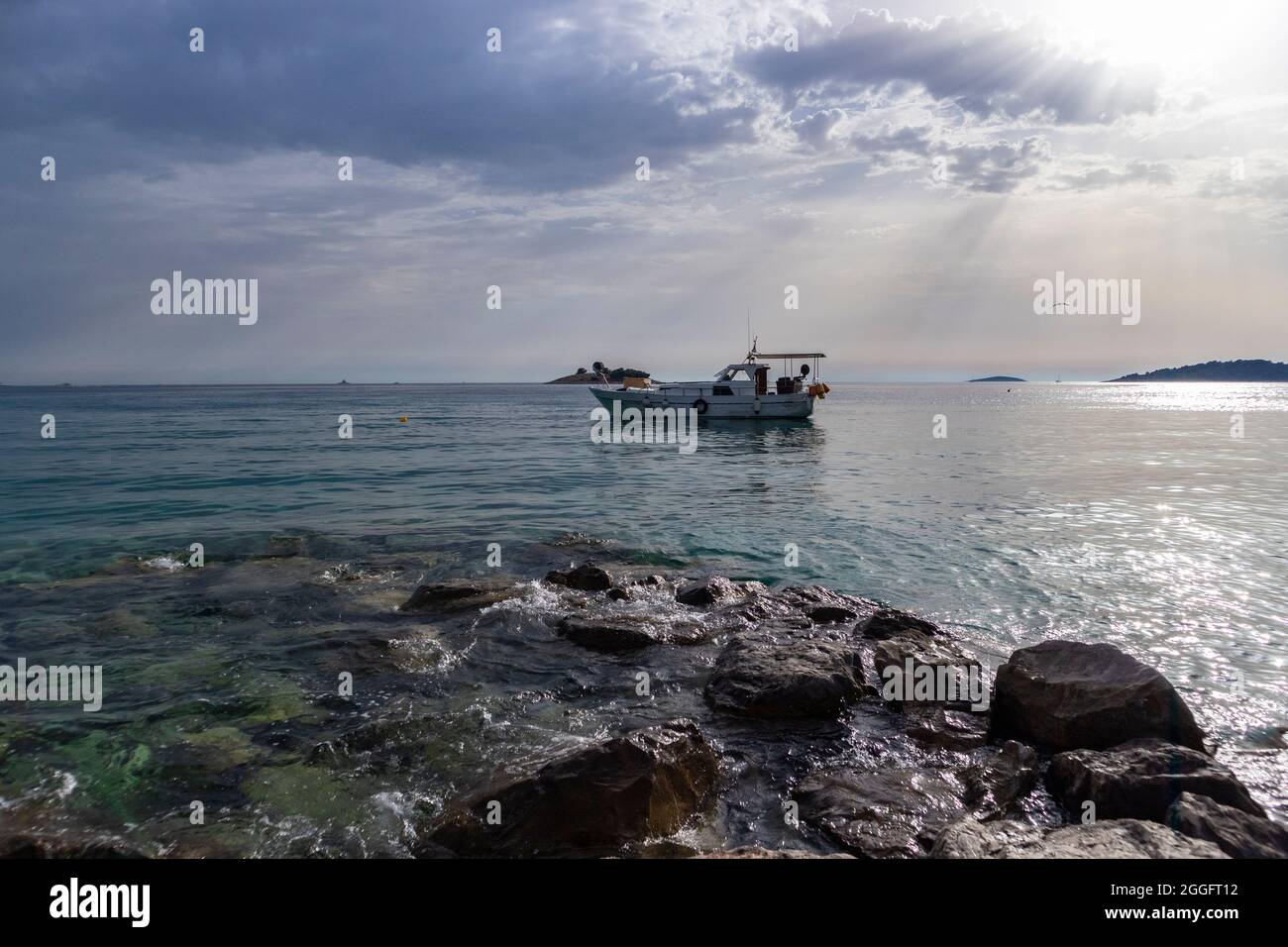 Fshing boat anchored at the open Adriatic sea with distant islands in the distance off the coast of Rogoznica, Croatia Stock Photo
