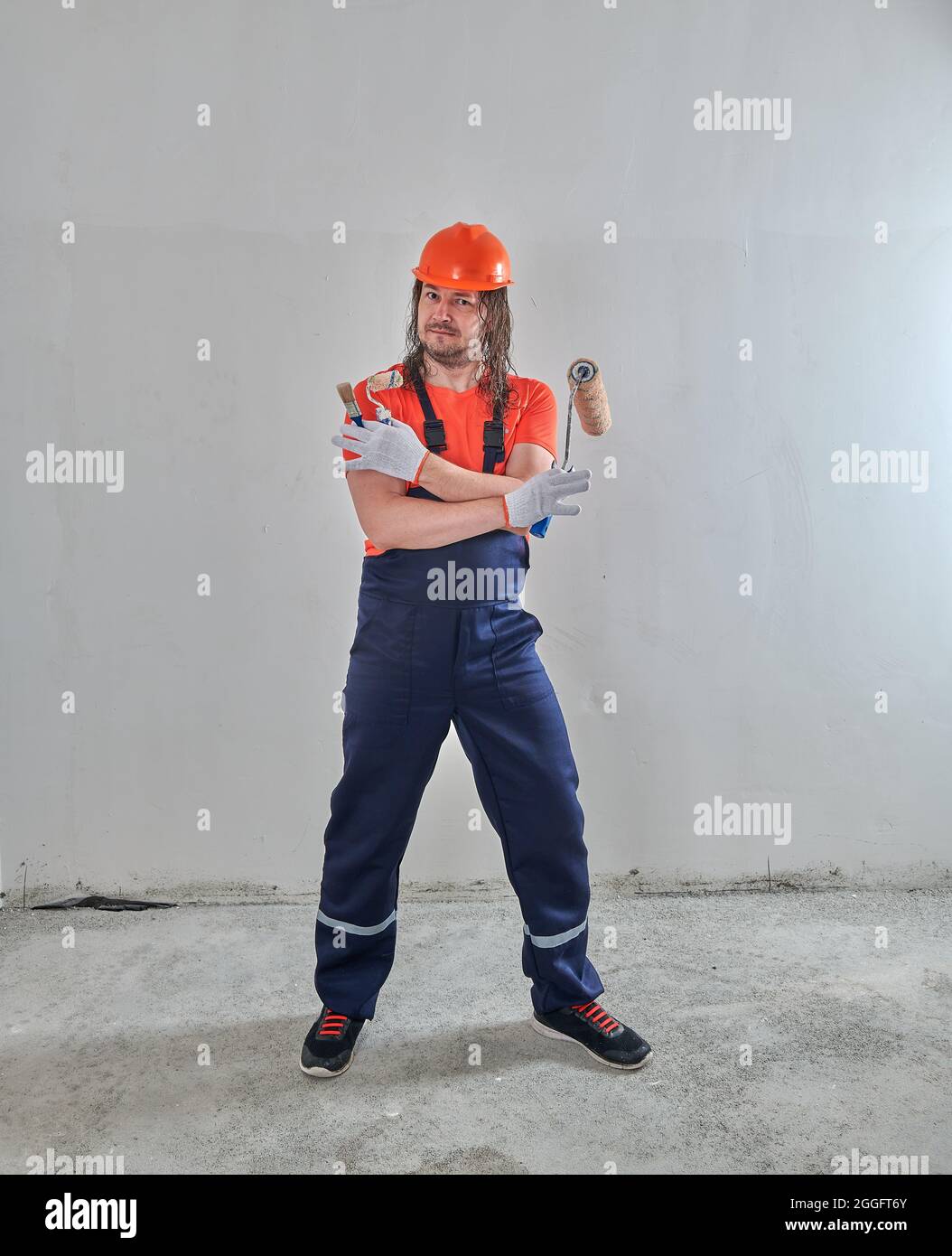 there is a painter in overalls with a roller and a brush Stock Photo