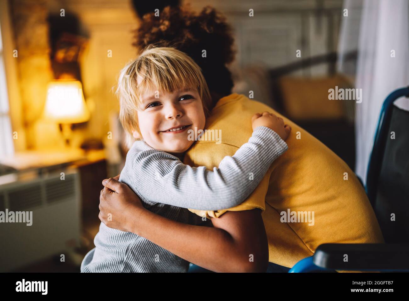 Happy multiethnic family. Smiling little girl with disability in wheelchair at home Stock Photo