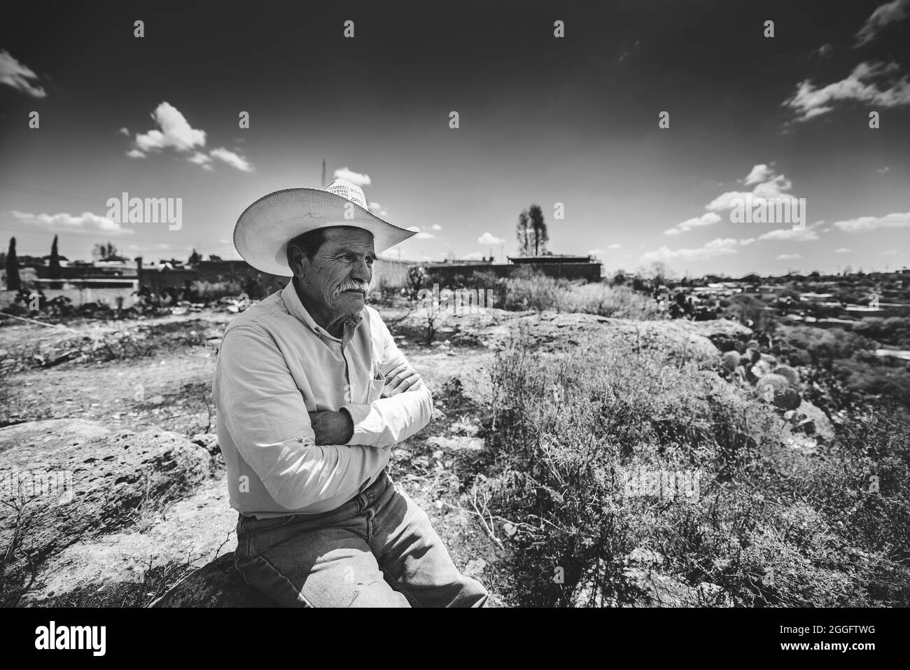 ZACATECAS, MEXICO - Apr 01, 2018: A grayscale shot of an old Hispanic with a cowboy hat sitting alone at a field in Zacatecas, Mexico Stock Photo