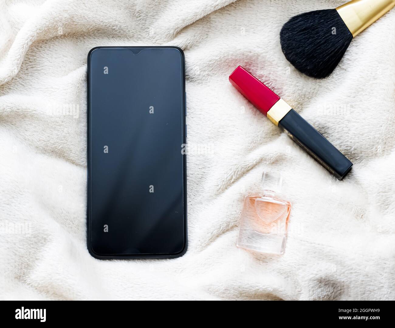 Make-up and mobile phone on white blanket in winter, smartphone flatlay ...