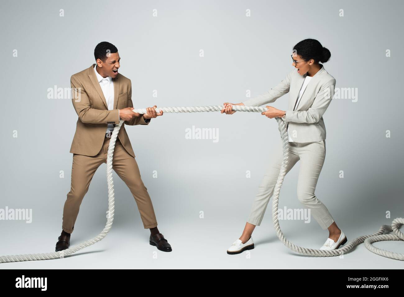 businessman and businesswoman pulling rope on grey, gender equality concept Stock Photo