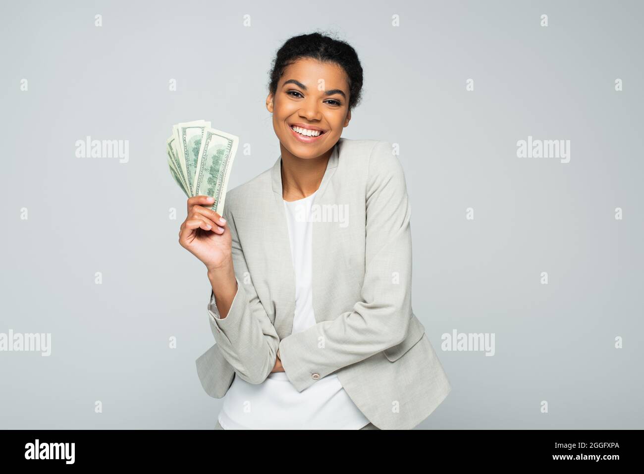 happy african american businesswoman holding dollar banknotes isolated on grey Stock Photo