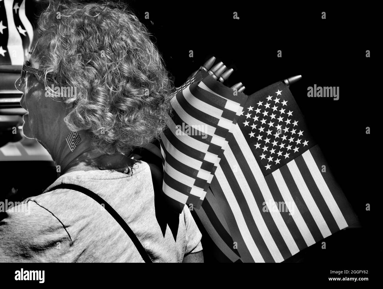 A woman distributes small American flags at a Fourth of July vintage car show in Santa Fe, New Mexico. Stock Photo