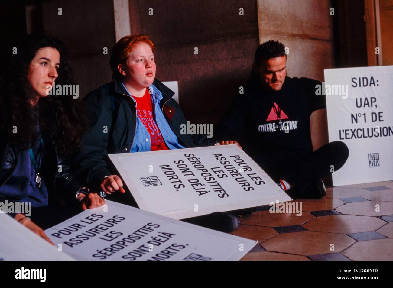 Act Up Paris Demonstration Against Discrimination by French Insurance Industry, Group of AIDS Activists blocking ENtrance in Lobby Holding Protest Signs, young activism, anti discrimination, activist girls, young lesbians 1990s women Stock Photo
