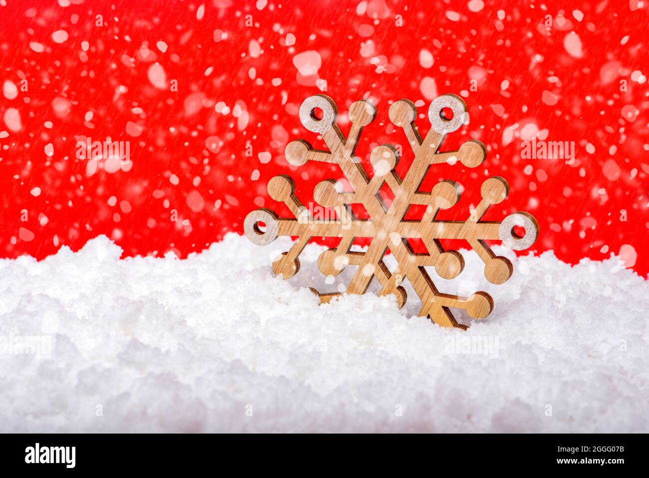 Snow on a red background, snowfall or falling snow. Large wooden snowflake in the snow. Christmas concept. New Year theme, panoramic photo for a Stock Photo