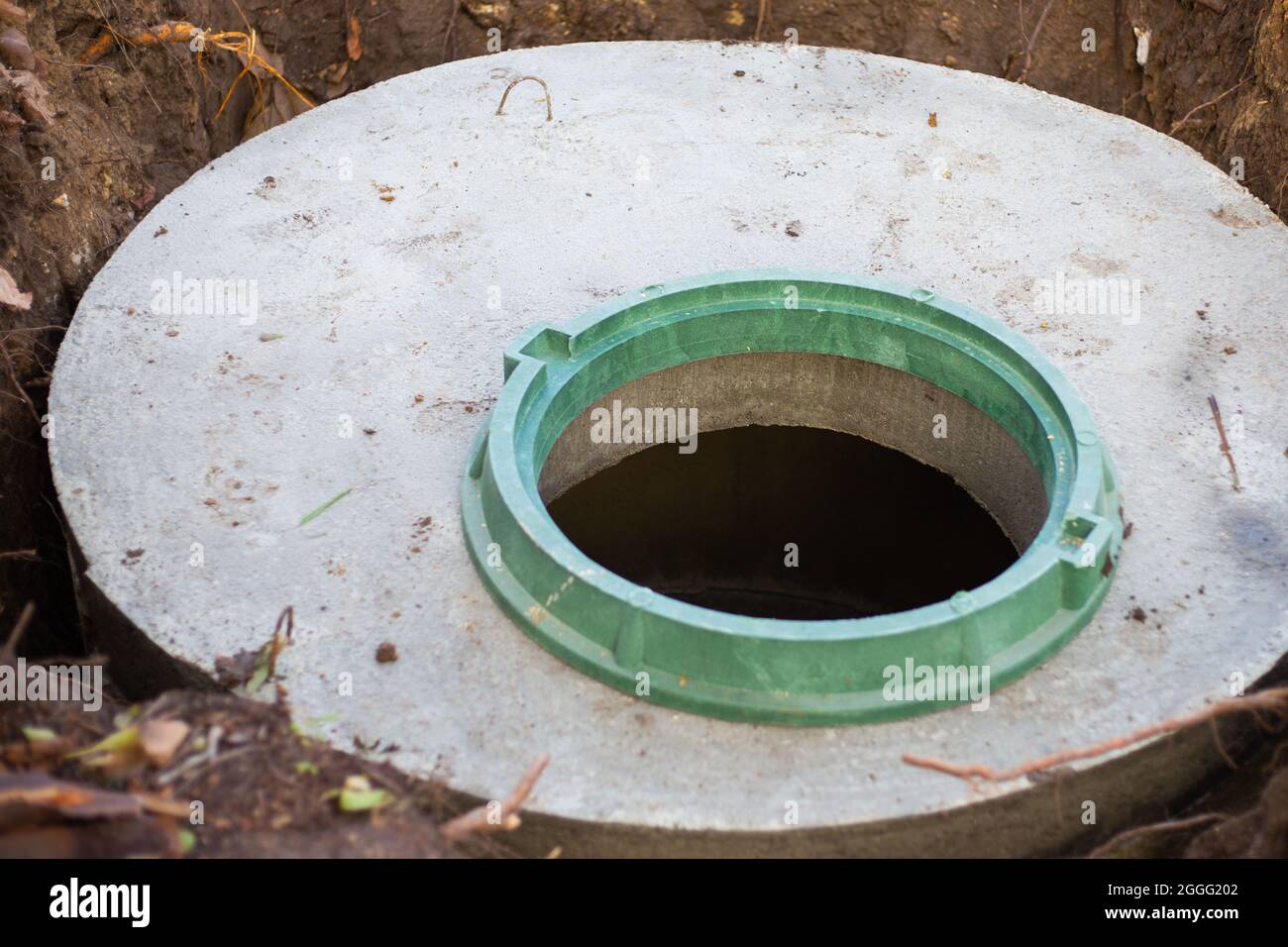 Construction of a septic tank. Large concrete rings embedded in the ground, from above an open sewer hatch, unprotected by a cover from falling. Stock Photo