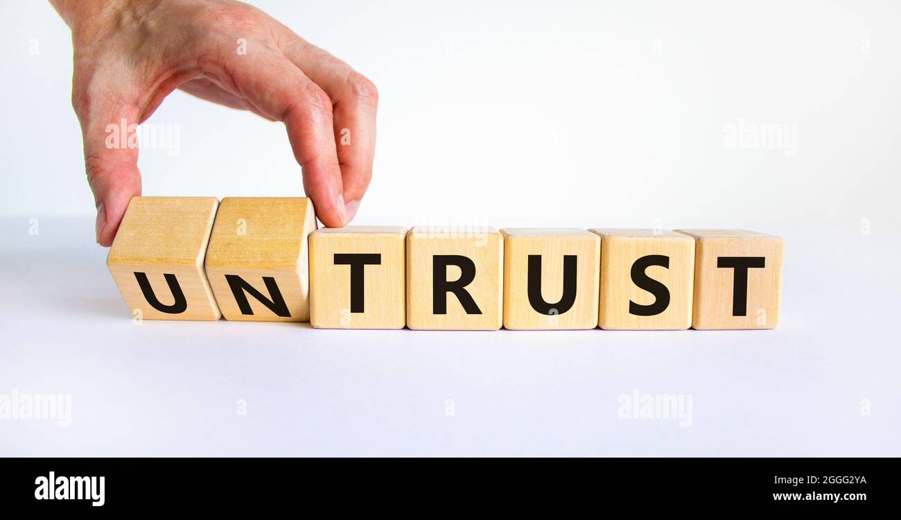 Untrust or trust symbol. Businessman turns wooden cubes, changes words 'untrust' to 'trust'. Beautiful white table, white background. Business and unt Stock Photo