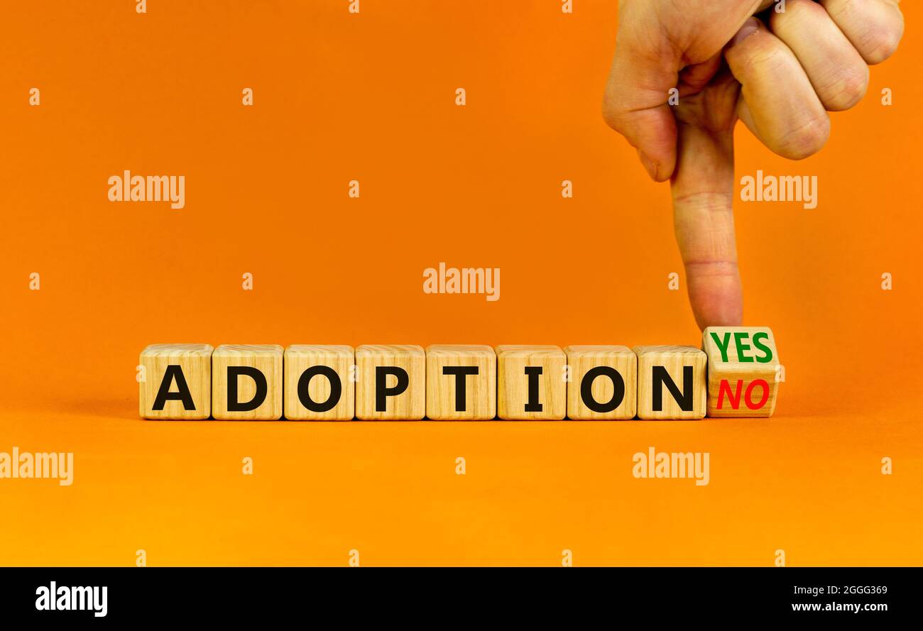 Adoption symbol. Businessman turns a wooden cube and change words 'adoption no' to 'adoption yes'. Beautiful orange background. Business and adoption Stock Photo