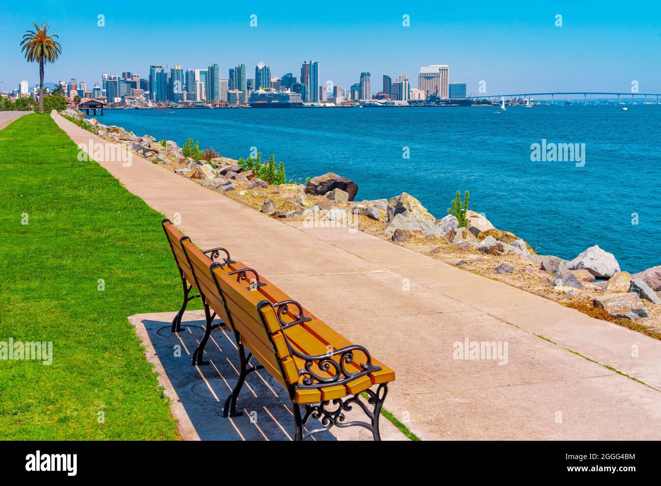 A sidewalk lines the waterfront of San Diego and beckons you to sit on a bench and look at the skyline and CoronadoBay Bridge. Stock Photo