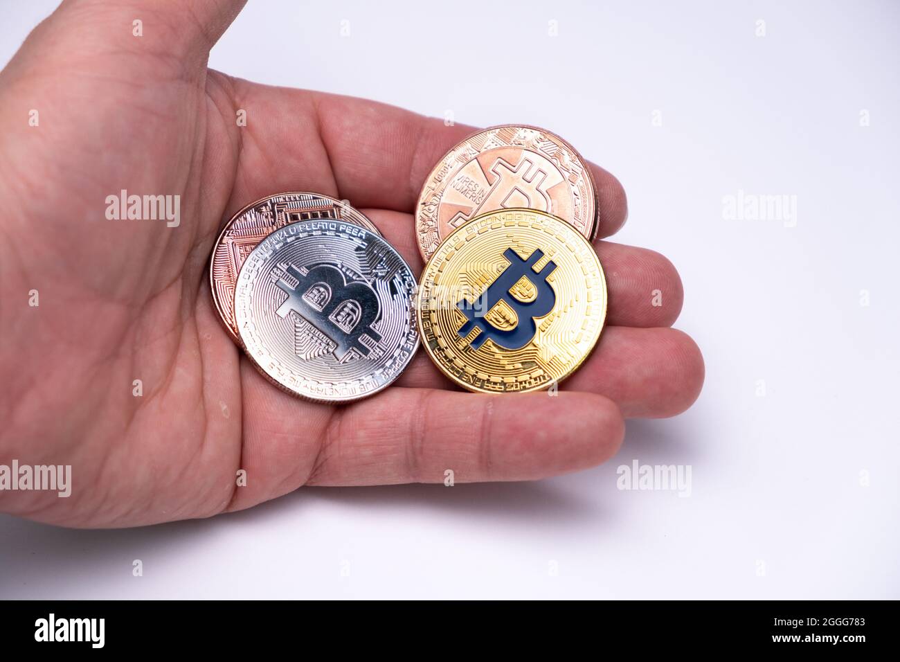 Lots of Bitcoins different colours on one hand palm. Cryptocurrency concept, bitcoin BTC standing on mens hand. Cryptocurrency lies on the palm hand. Stock Photo