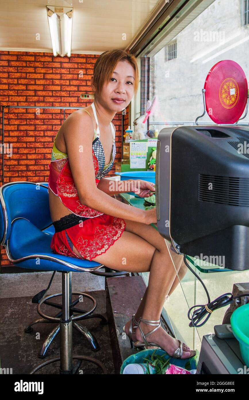 Betel nut beauty (binlang girl) selling betel nut leaf from glass kiosk at side of highway, Caotun, Taiwan Stock Photo