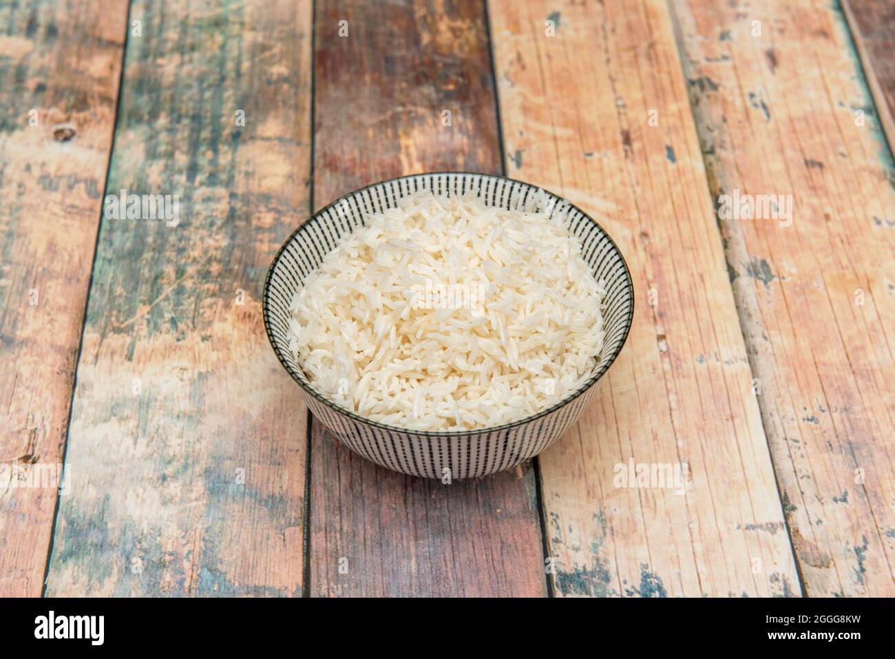 Bowl pequeño de arroz blanco listo para servir de guarnicion sobre fondo de madera Stock Photo