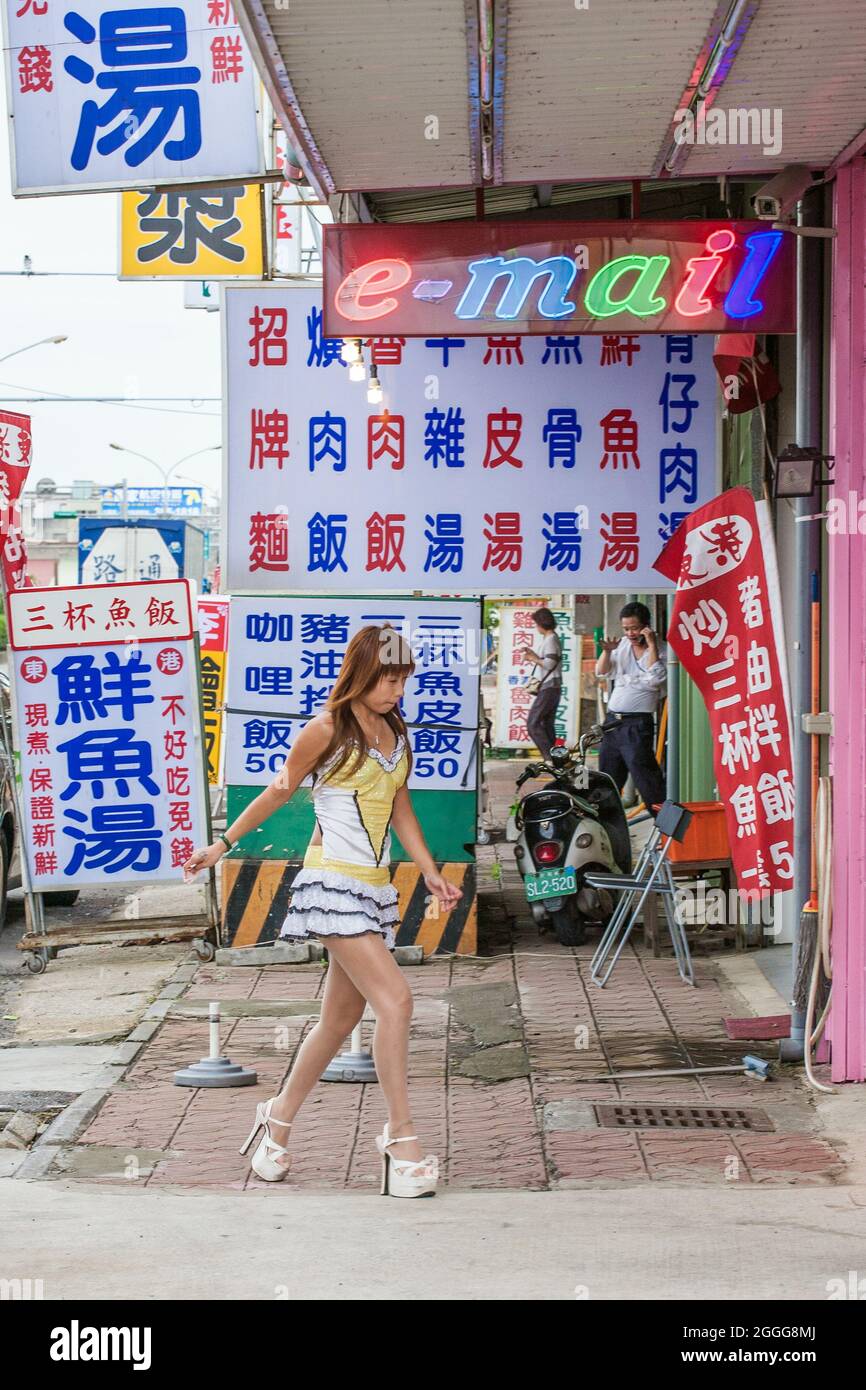 Betel nut beauty (binlang girl) selling betel nut leaf walks to her glass kiosk at side of highway, Taipei, Taiwan Stock Photo