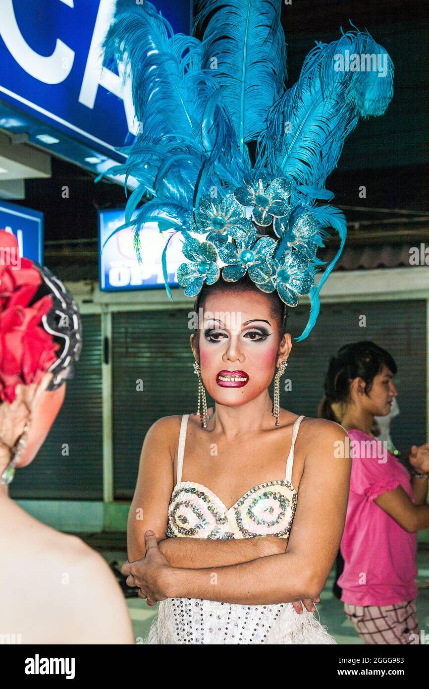 Thai ladyboy with underbite in sparkly colourful costume with flamboyant headdress on street before performing cabaret on stage, Phuket, Thailand Stock Photo