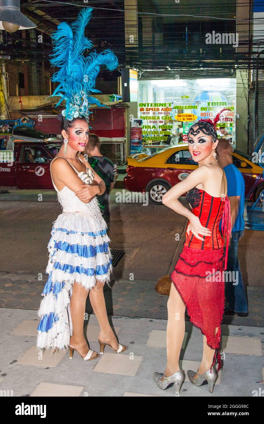 Thai ladyboys dressed in sparkly colourful costumes with flamboyant headdresses stand on street before performing cabaret on stage, Phuket, Thailand Stock Photo