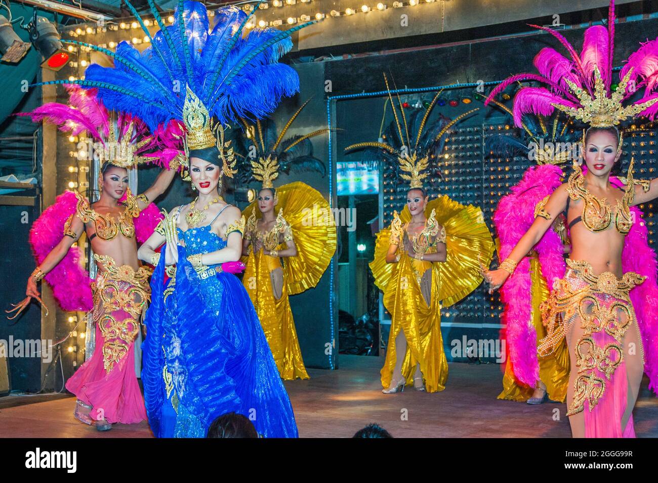 Thai ladyboys dressed in sparkly colourful costumes with flamboyant headdresses performing cabaret numbers on stage, Phuket, Thailand Stock Photo