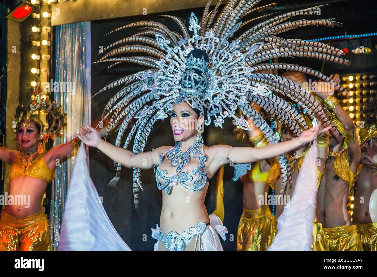Thai ladyboy dressed in sparkly costume exposing silicon breasts with flamboyant headdress performing cabaret numbers on stage, Phuket, Thailand Stock Photo