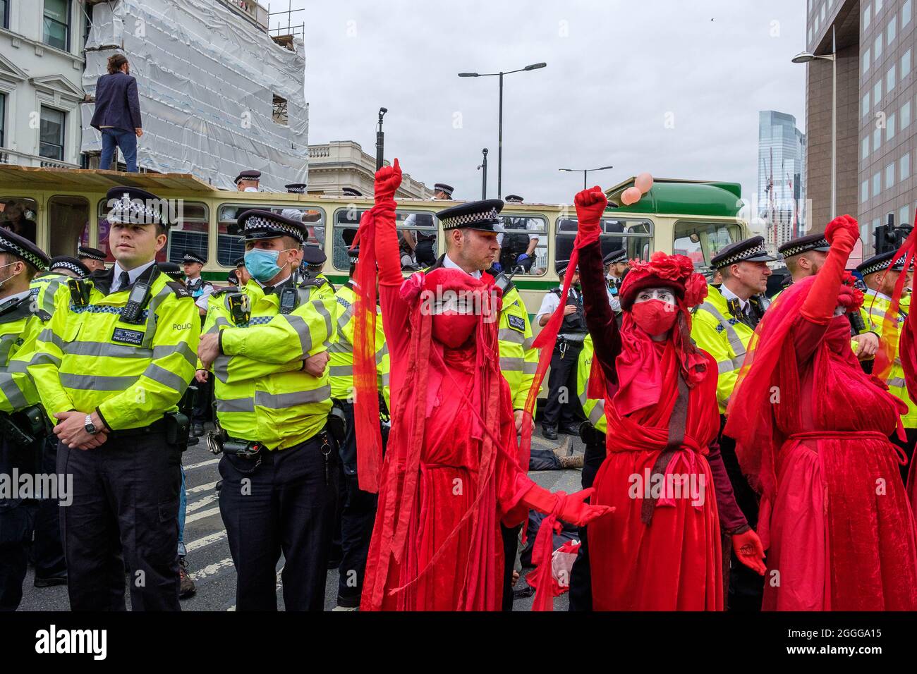 London, UK. 31st August 2021. Red Rebel Brigade faces the police. Extinction Rebellion protest blocks London Bridge using a wedding bus. Credit: Joao Daniel Pereira Stock Photo