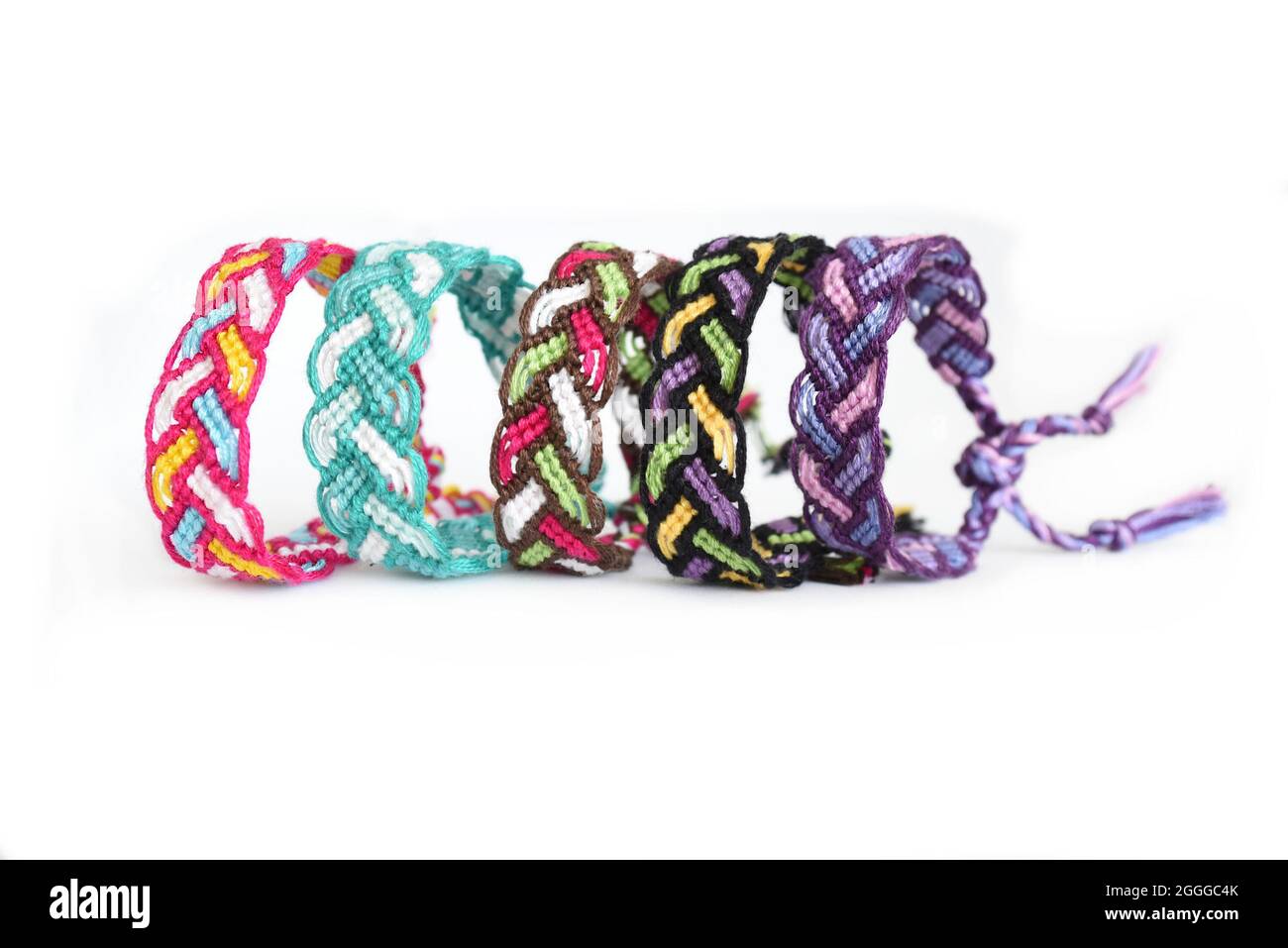 Multicolored woven DIY friendship bracelets Pigtail handmade of embroidery bright thread with knots isolated on white background Stock Photo