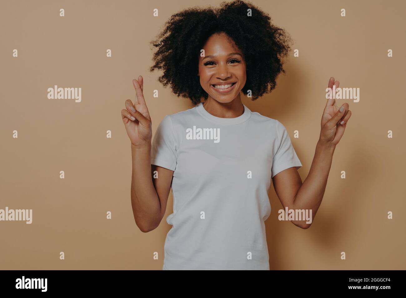 Hopeful african american female isolated on beige studio background crossing fingers making wish Stock Photo