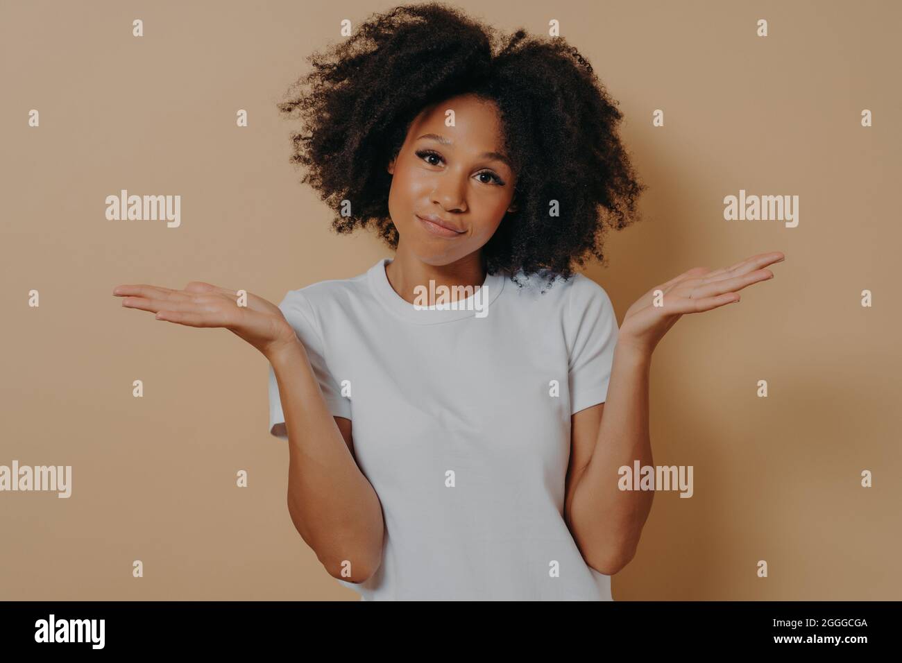 Mixed race female being unsure and having some doubts while posing against beige wall Stock Photo