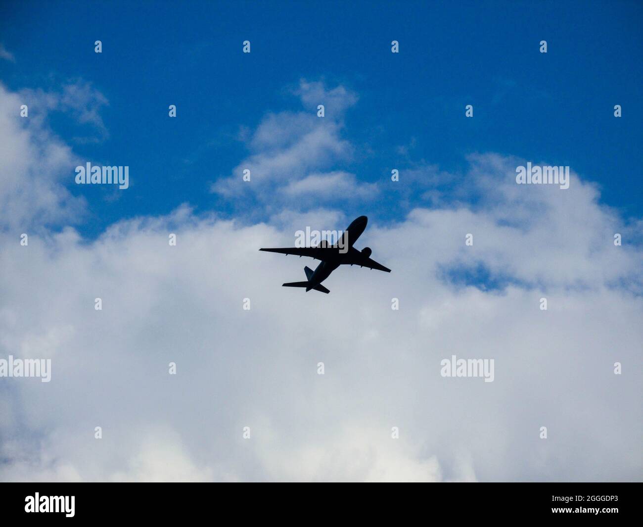 Silhouette of airplane flying in blue sky with white clouds in Vietnam Stock Photo