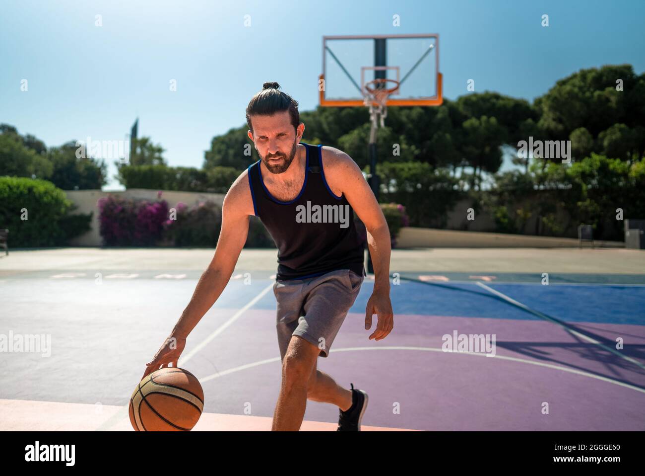 Fit male playing basketball outdoor, sunny weather, modern playground. Wide lense shot Stock Photo