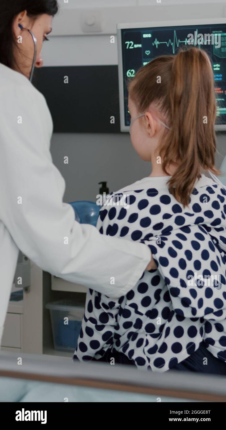 Pediatrician woman doctor examining sick patient using medical stethoscope listening heart beat