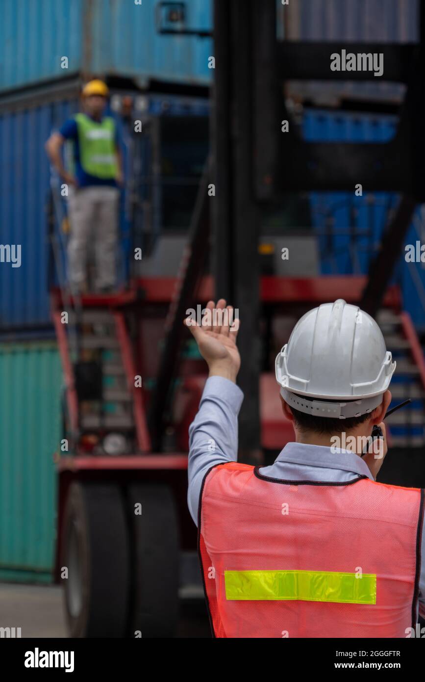 Industrial worker works with co-worker at overseas shipping container yard . Logistics supply chain management and international goods export concept Stock Photo