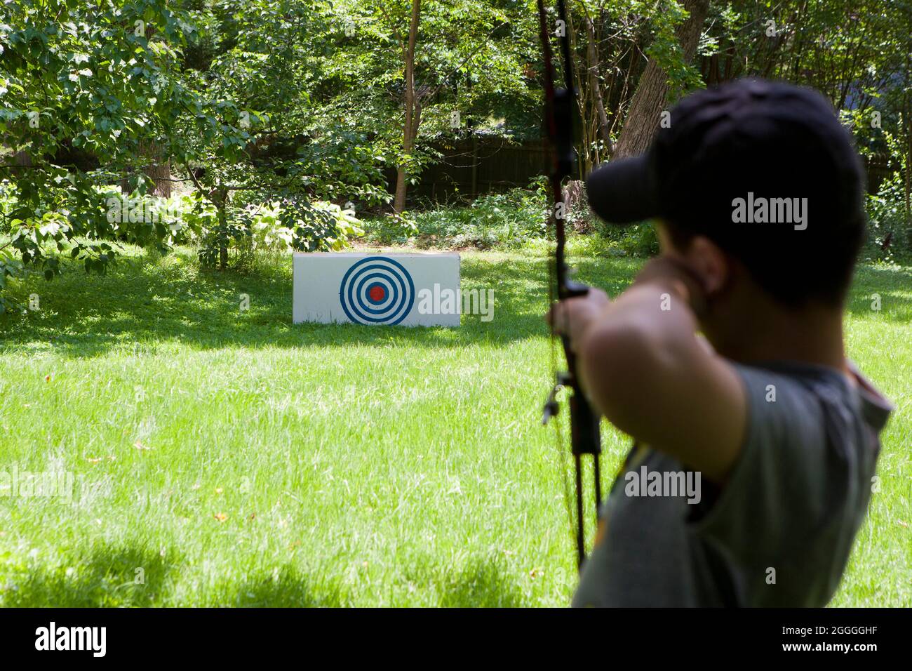 Young boy practicing archery in back yard of home - USA Stock Photo