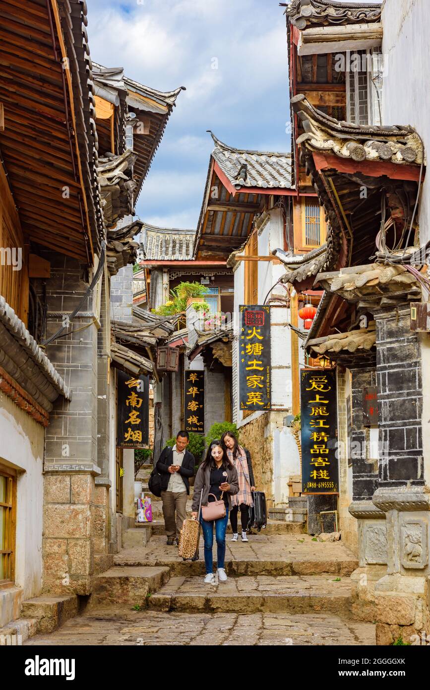 Yunnan, China - 22 March 2016: Tourists walking along street of historical shophouses in Lijiang ancient town. Stock Photo