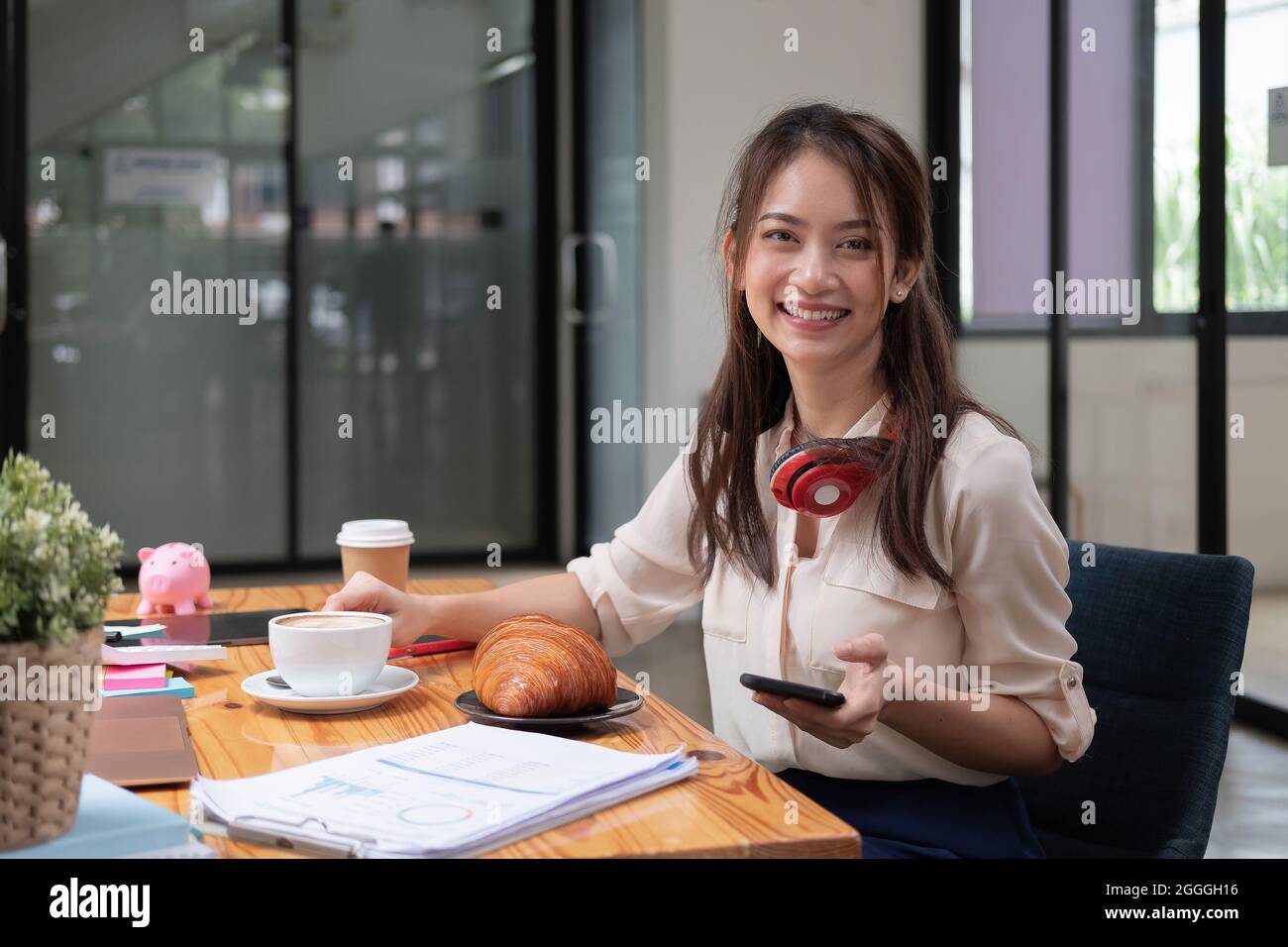 Beautiful young Asian girl working at a office space with a mobile phone. Concept of smart female business accounting Stock Photo