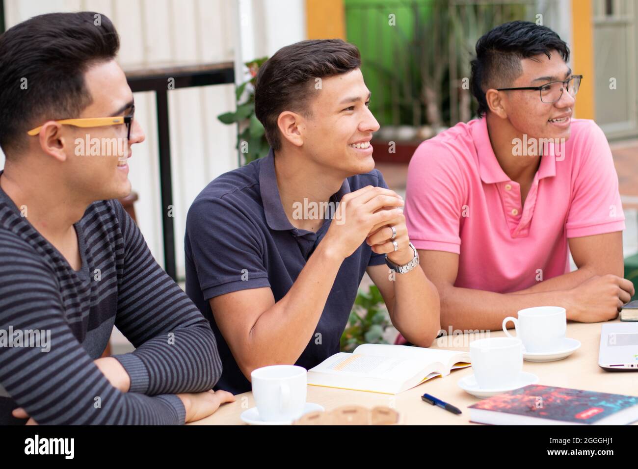 three latin students looking at the same place and smiling Stock Photo