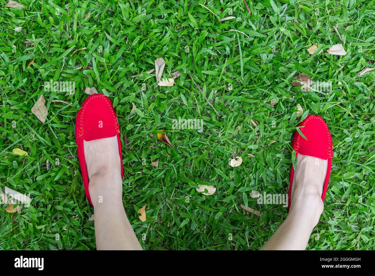 Red shoes girl on green grass background Stock Photo - Alamy